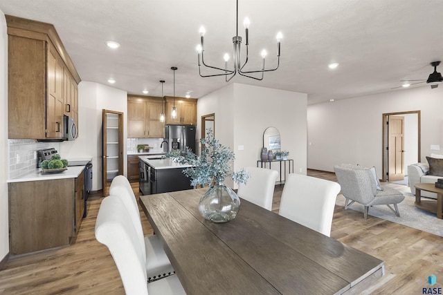 dining room with light wood-style floors, ceiling fan with notable chandelier, and recessed lighting