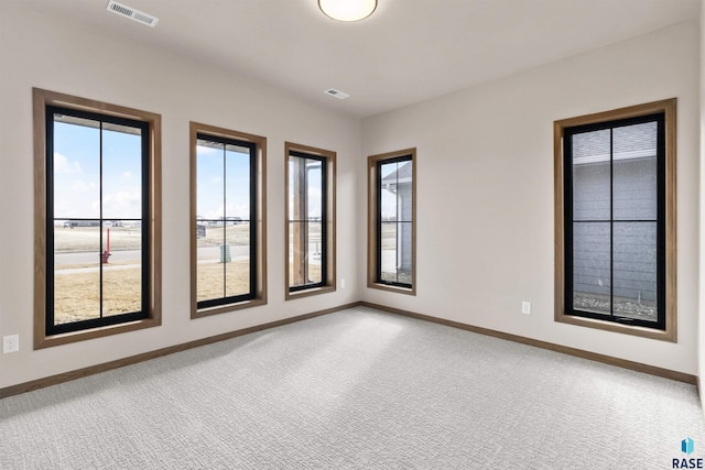 empty room featuring visible vents, light carpet, and baseboards