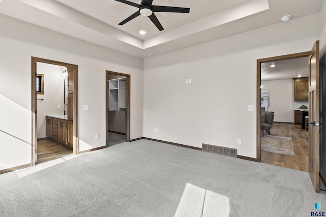 bedroom with baseboards, visible vents, a raised ceiling, and light colored carpet