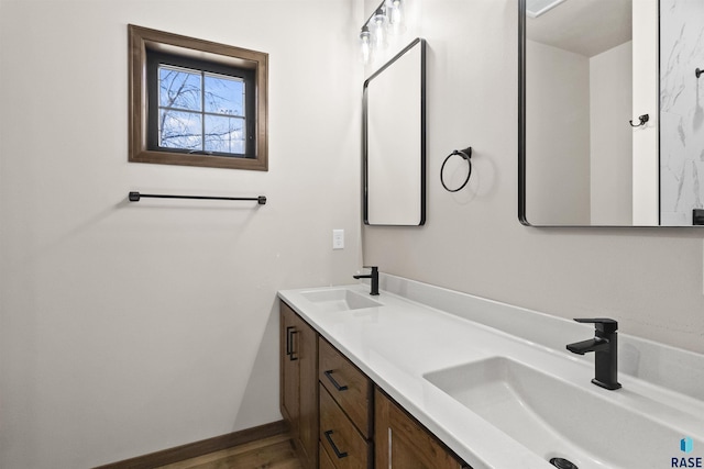 full bathroom with a sink, baseboards, and double vanity