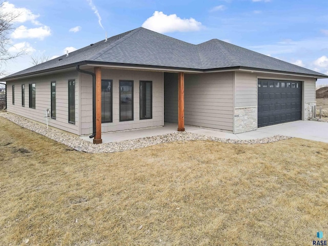 view of front of house featuring a shingled roof, a front yard, stone siding, and an attached garage