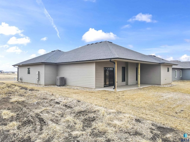 back of house featuring a patio area, central AC unit, and roof with shingles