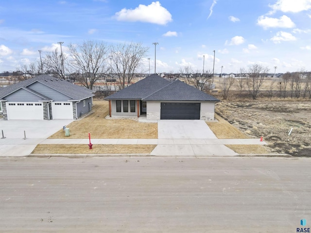 view of front facade with an attached garage, a shingled roof, concrete driveway, and brick siding