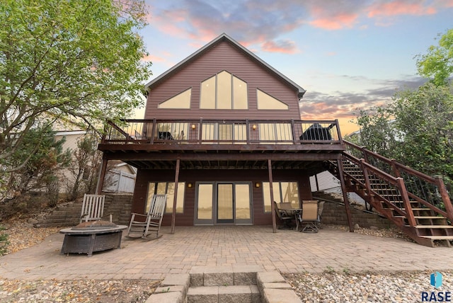 back house at dusk featuring a deck, a fire pit, and a patio area