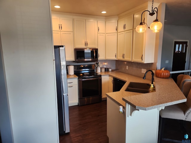 kitchen featuring pendant lighting, kitchen peninsula, appliances with stainless steel finishes, and a breakfast bar area