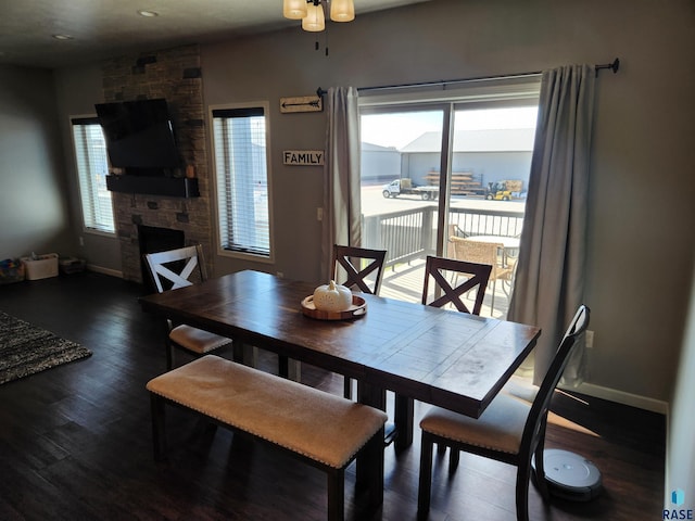 dining space featuring ceiling fan, dark hardwood / wood-style floors, and a stone fireplace