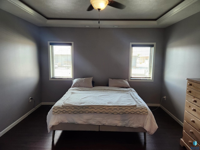 bedroom featuring ceiling fan, a tray ceiling, dark hardwood / wood-style floors, and multiple windows