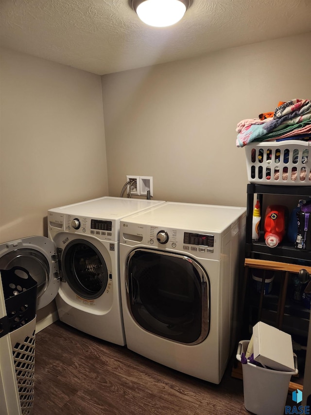 washroom with a textured ceiling, washer and dryer, and dark wood-type flooring