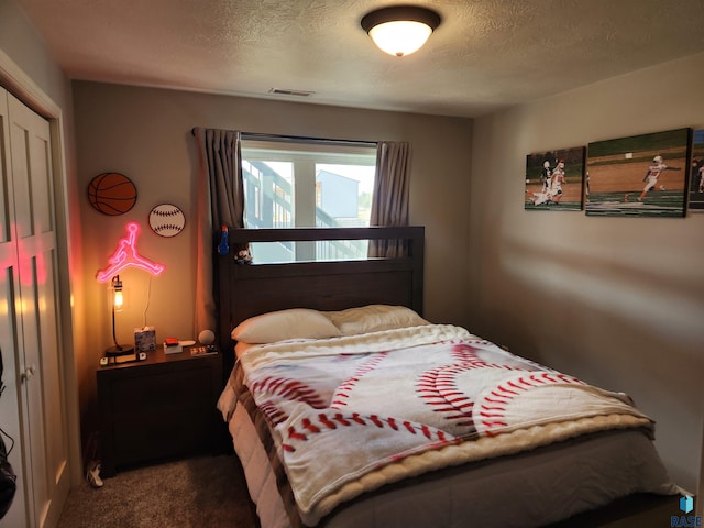 bedroom featuring dark carpet and a textured ceiling