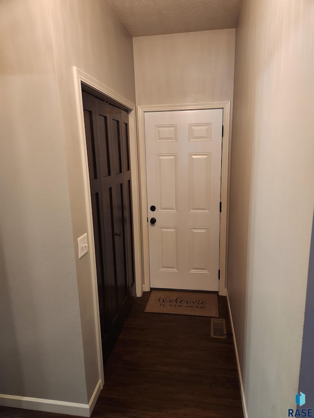 doorway featuring a textured ceiling and dark wood-type flooring