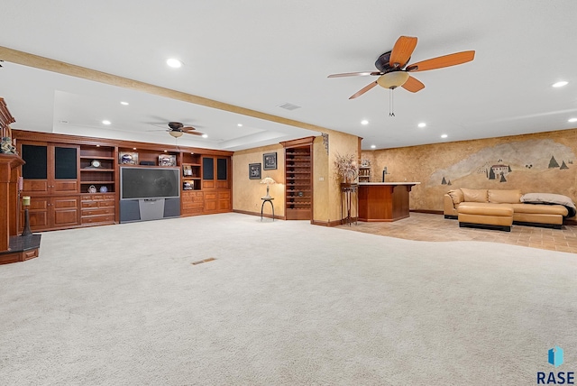 unfurnished living room with light carpet, a raised ceiling, bar, and ceiling fan