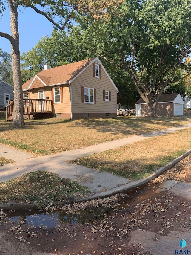 view of front of property with an outdoor structure, a deck, and a front lawn