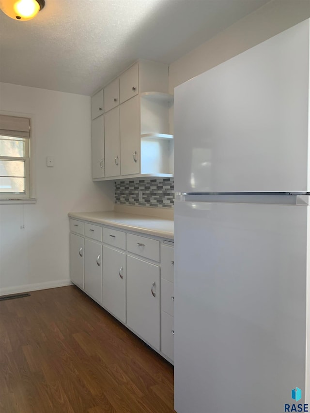 kitchen featuring white refrigerator, white cabinets, dark hardwood / wood-style flooring, and decorative backsplash