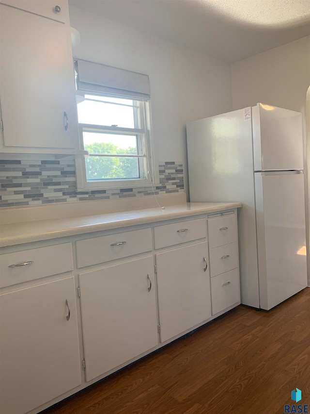 kitchen featuring decorative backsplash, dark hardwood / wood-style floors, white cabinets, white fridge, and a textured ceiling