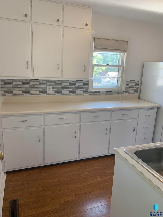 kitchen with decorative backsplash, white refrigerator, dark hardwood / wood-style flooring, and white cabinetry