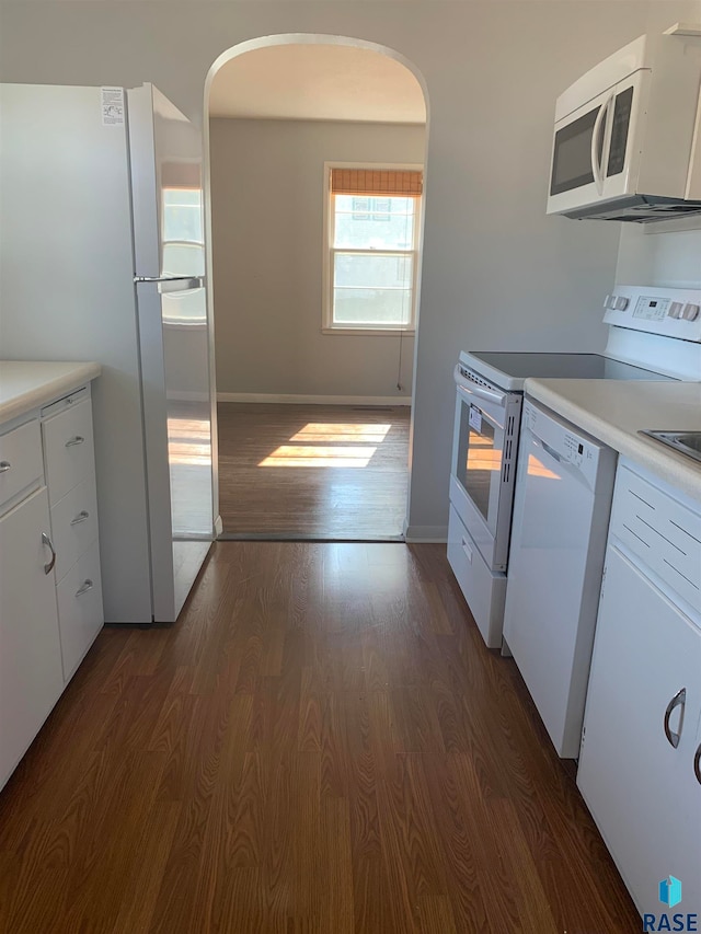 kitchen featuring white appliances, dark hardwood / wood-style flooring, and white cabinetry