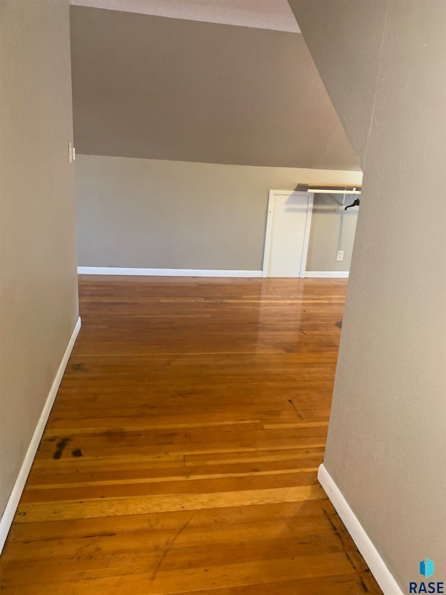 hallway featuring vaulted ceiling and hardwood / wood-style flooring