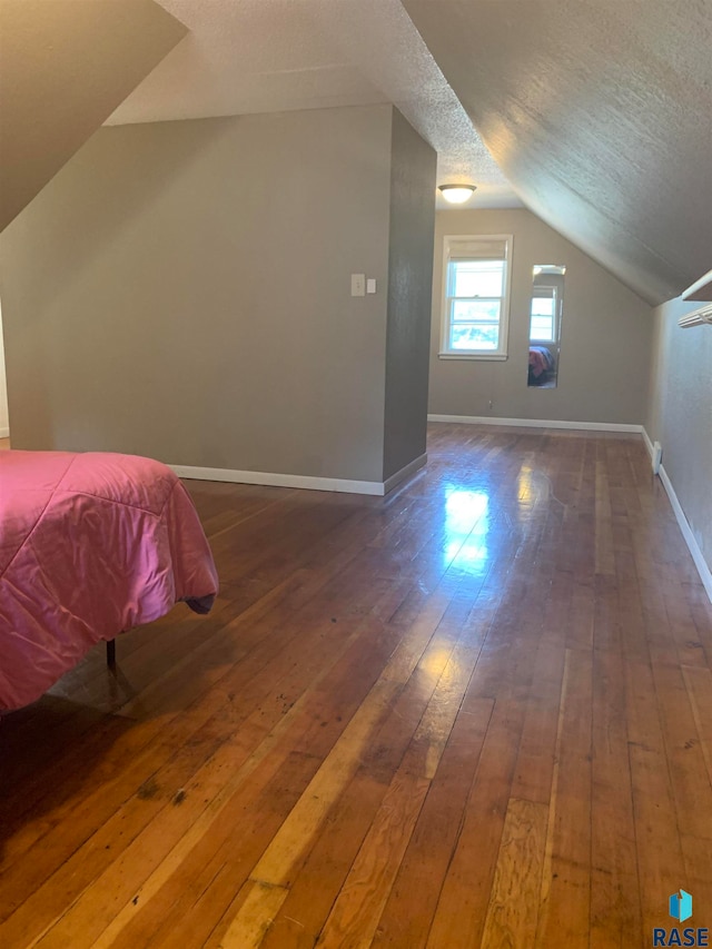 interior space with a textured ceiling, lofted ceiling, and dark hardwood / wood-style flooring