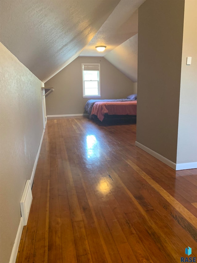 unfurnished bedroom featuring vaulted ceiling, dark hardwood / wood-style flooring, and a textured ceiling