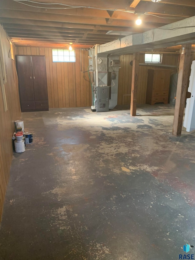 basement featuring heating unit and wooden walls