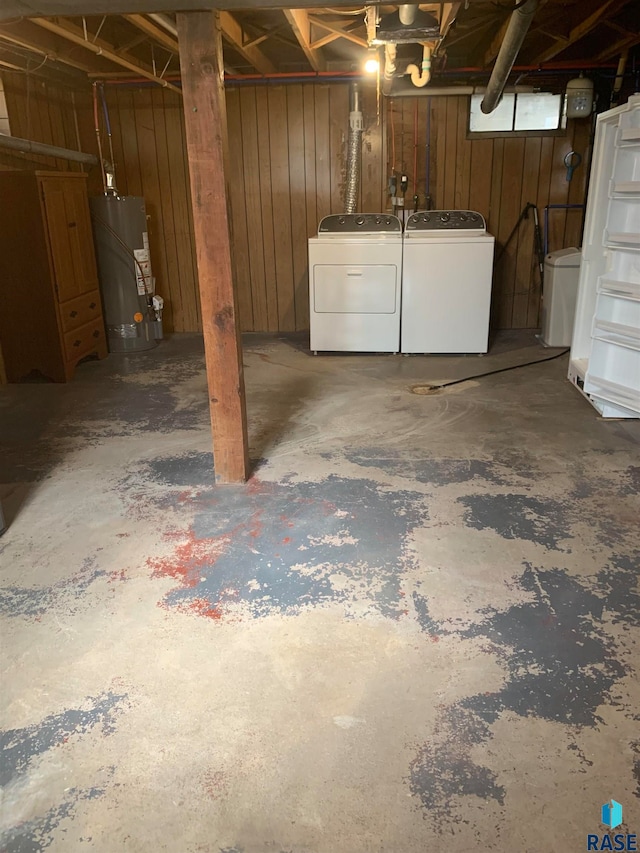 basement with gas water heater, wooden walls, and independent washer and dryer