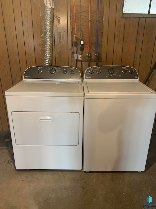 laundry room with wooden walls and washer and clothes dryer