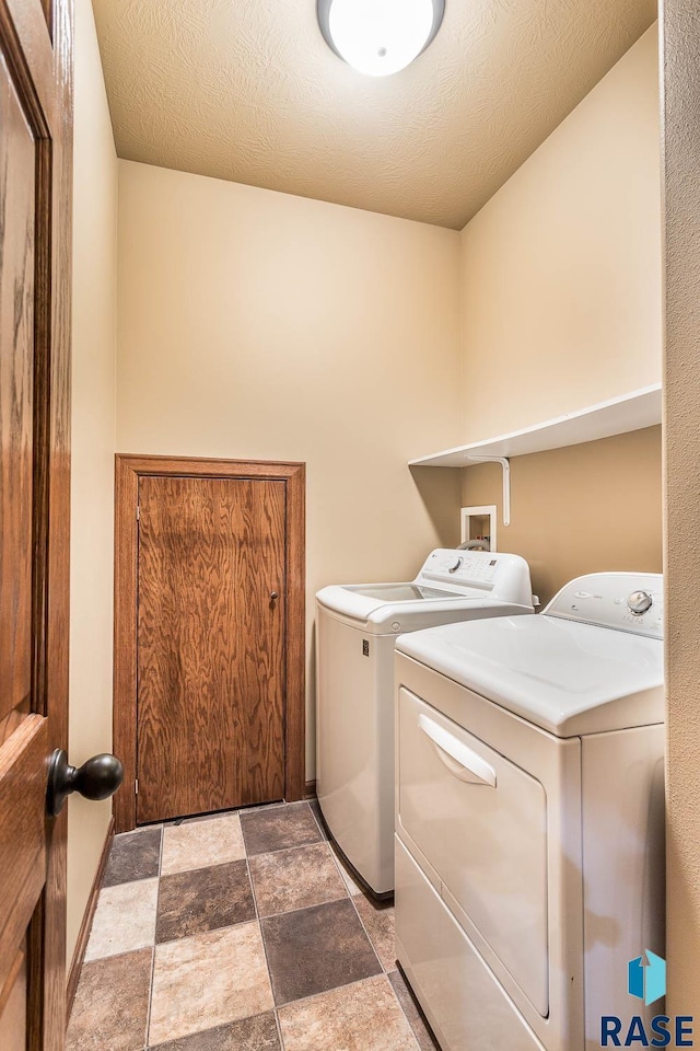 clothes washing area featuring a textured ceiling and washing machine and dryer