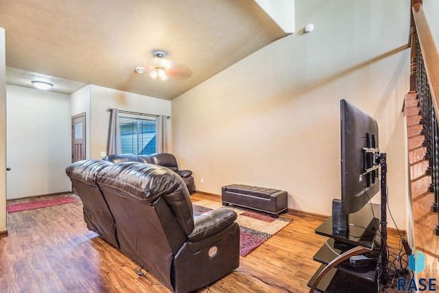 living room with hardwood / wood-style flooring, ceiling fan, and a textured ceiling