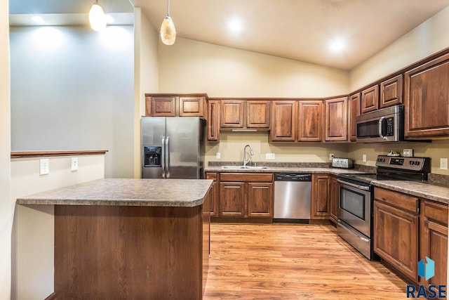 kitchen featuring stainless steel appliances, hanging light fixtures, light hardwood / wood-style floors, and lofted ceiling