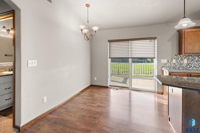 unfurnished dining area with a notable chandelier, wet bar, and dark hardwood / wood-style flooring