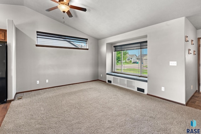 unfurnished living room featuring ceiling fan, a textured ceiling, dark colored carpet, and vaulted ceiling