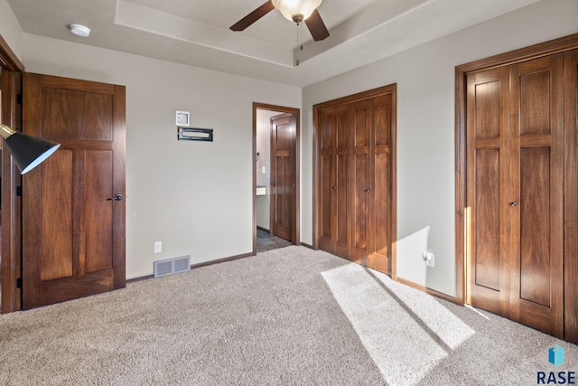 unfurnished bedroom featuring ceiling fan, a tray ceiling, and carpet flooring