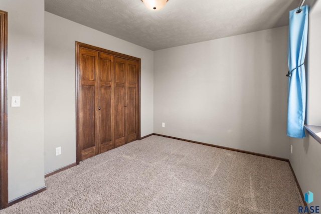 unfurnished bedroom with a textured ceiling, a closet, and light colored carpet