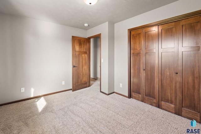 unfurnished bedroom featuring a closet, a textured ceiling, and light carpet