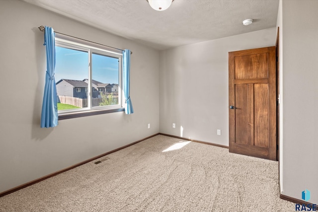 carpeted spare room with a textured ceiling