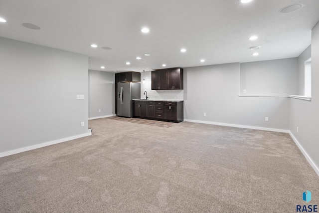 unfurnished living room featuring sink and light carpet