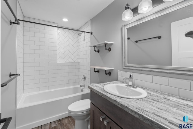 full bathroom with tiled shower / bath, vanity, tasteful backsplash, wood-type flooring, and toilet