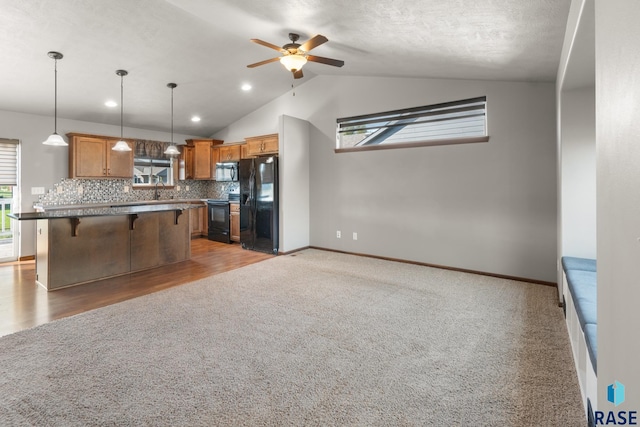 kitchen with ceiling fan, black fridge, a breakfast bar, range with electric stovetop, and a center island