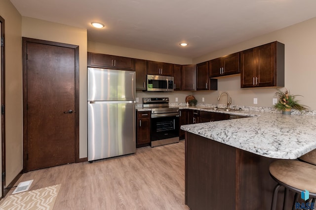 kitchen featuring light hardwood / wood-style floors, stainless steel appliances, sink, and kitchen peninsula