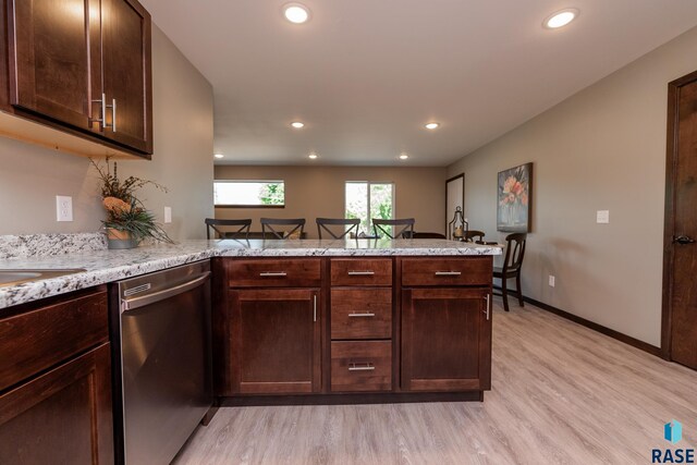 kitchen with light hardwood / wood-style flooring, dark brown cabinets, light stone countertops, kitchen peninsula, and stainless steel dishwasher