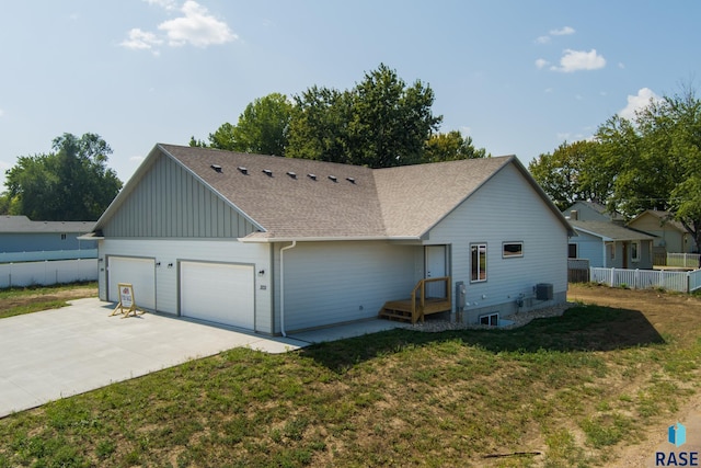 ranch-style home with a front lawn, cooling unit, and a garage