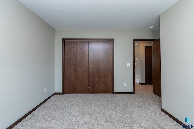 unfurnished bedroom with light carpet and a closet