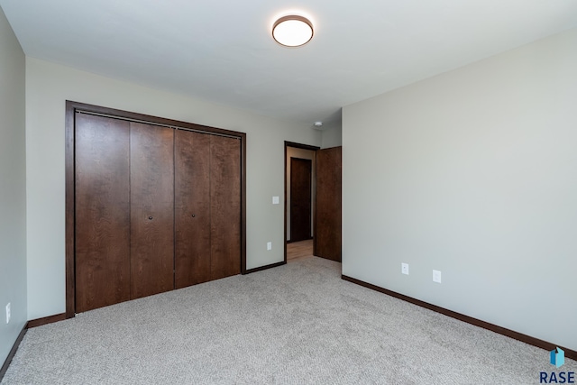 unfurnished bedroom featuring light carpet and a closet