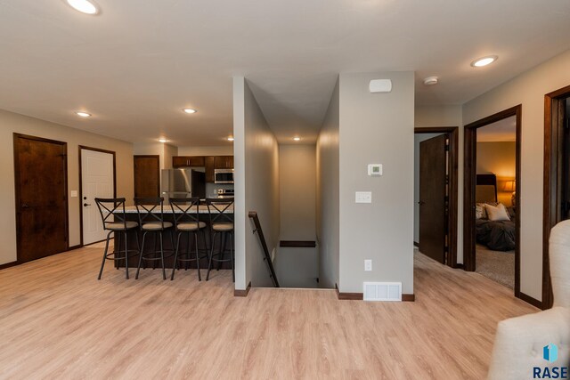 kitchen with appliances with stainless steel finishes, light wood-type flooring, and a breakfast bar