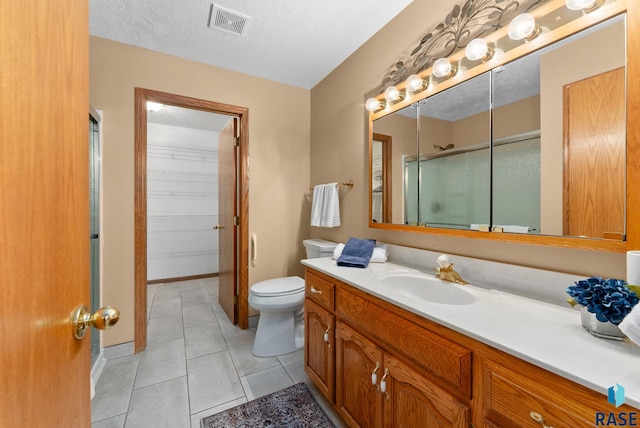 bathroom with a shower with door, a textured ceiling, vanity, tile patterned floors, and toilet