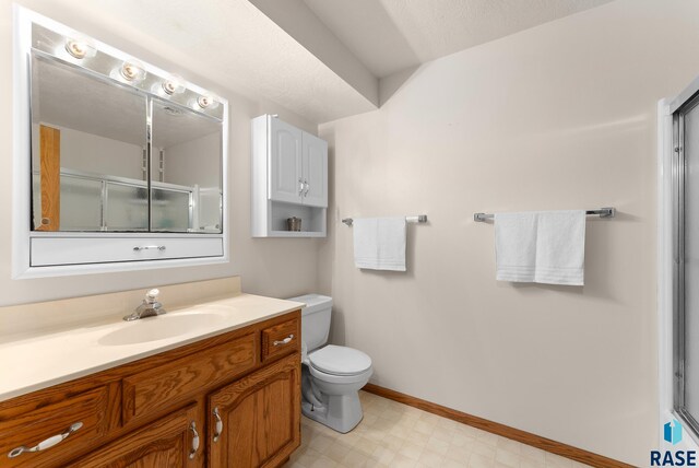 bathroom with a shower with door, vanity, and toilet