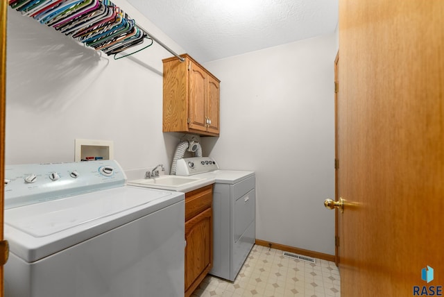 clothes washing area featuring cabinets, a textured ceiling, sink, and washer and clothes dryer