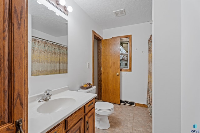 bathroom featuring tile patterned floors, vanity, toilet, and a textured ceiling