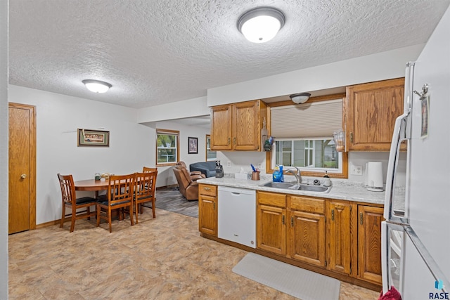 kitchen featuring a textured ceiling, white appliances, sink, and a wealth of natural light