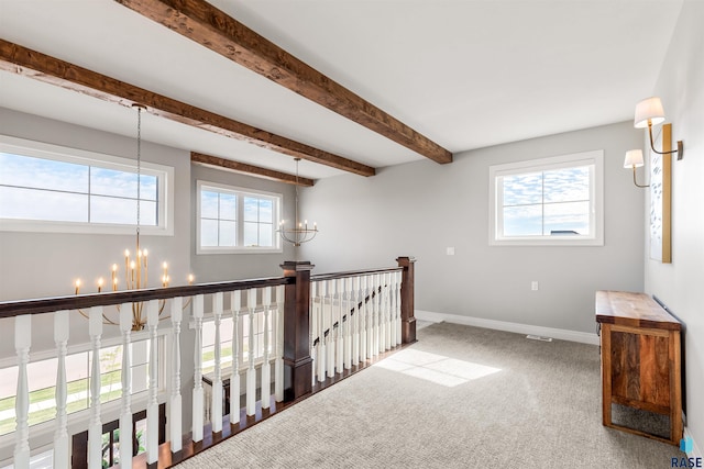 hallway featuring beam ceiling, a chandelier, and carpet